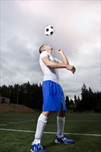 Hispanic athlete heading soccer ball