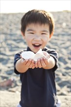Chinese boy holding out handful of shells
