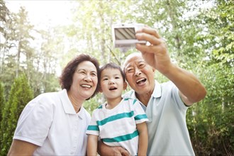 Chinese grandparents taking self-portrait with grandson