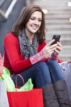 Mixed race woman shopping and text messaging on cell phone