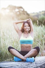 Mixed race woman stretching in field