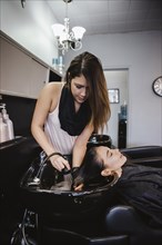 Stylist washing client's hair in salon
