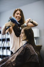 Stylist blow drying client's hair in salon