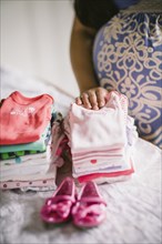 Pregnant Asian woman folding baby clothes