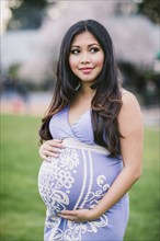 Asian woman holding her pregnant belly