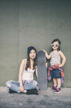 Korean mother and daughter posing with skateboard