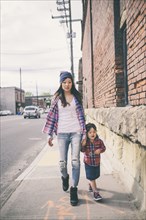 Korean mother and daughter holding hands on city street