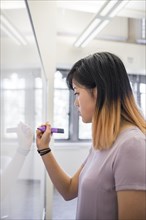 Chinese woman writing on whiteboard with marker