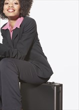 Businesswoman sitting on metal briefcase