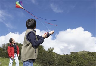 Asian father and son flying a kite