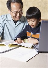 Asian father helping young son with homework