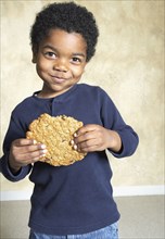 Young African American boy eating large cookie
