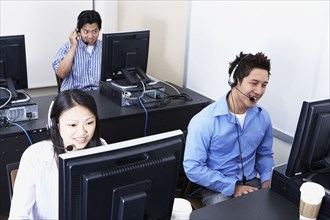 Three young Asian computer service technicians with headsets