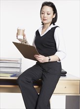 Studio shot of Asian businesswoman with clipboard