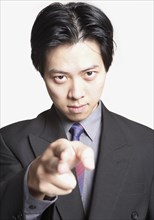 Studio shot of Asian businessman pointing finger