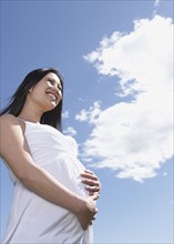 Low angle view of pregnant Asian woman under blue sky
