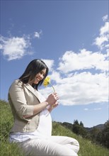 Pregnant Asian woman holding flower outdoors