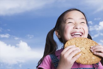 Young Asian girl holding cookie outdoors