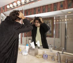Hispanic man looking in bathroom mirror