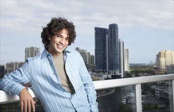 Hispanic man leaning against balcony