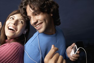 Hispanic couple listening to same mp3 player