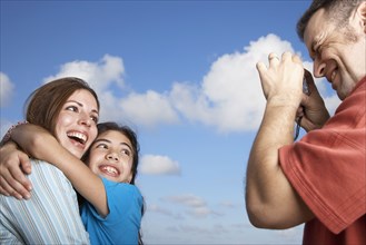 Hispanic father taking photograph of family