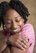 African woman hugging self