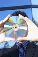 Asian businessman looking through center of cd
