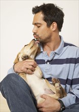 Mixed Race man kissing dog
