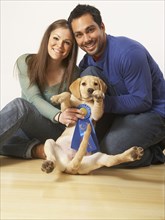 Multi-ethnic couple holding puppy dog and blue ribbon