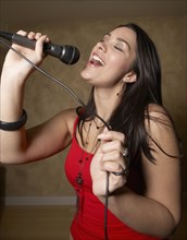 Hispanic woman singing with microphone