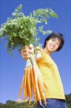 Asian man holding bunch of carrots