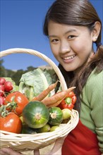 Asian woman holding basket of fresh vegetables