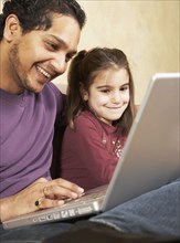 Indian father and daughter looking at laptop
