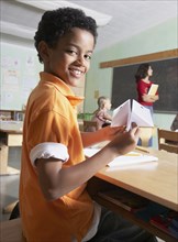 Mixed Race boy holding paper airplane in class