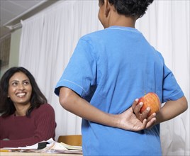 Mixed Race boy giving apple to teacher