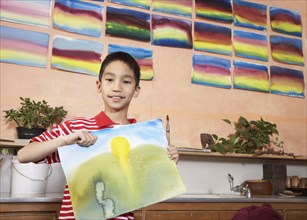 Asian boy holding painting