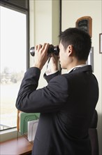 Asian businessman looking through binoculars