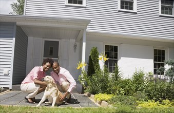 African couple and dog in front of house