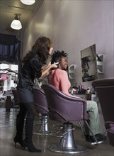 Hispanic hair stylist styling African woman's hair
