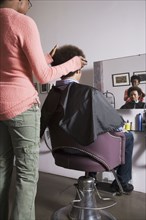 African hair stylist cutting Mixed Race man's hair