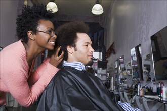 African hair stylist styling Mixed Race man's hair