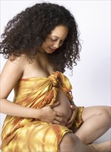 Pregnant Mixed Race woman looking at belly