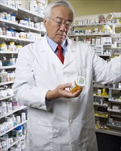 Senior Asian pharmacist reading medication