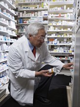 Senior Asian pharmacist looking at medication