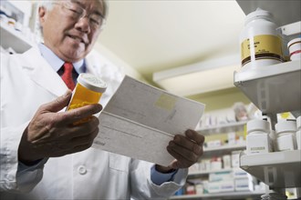 Senior Asian pharmacist reading prescription