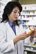 Asian pharmacist reading medication