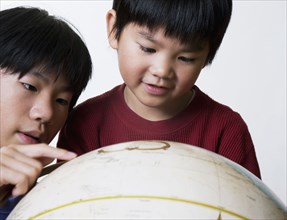 Asian brothers looking at globe