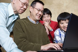 Multi-generational Asian family looking at laptop