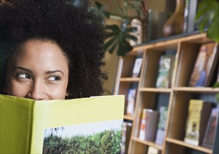 African woman looking over top of book